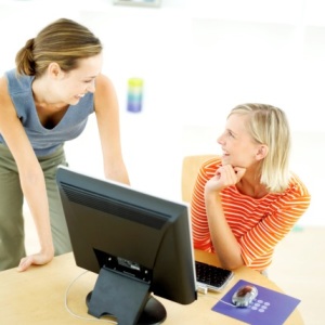 two women talking in front of computer